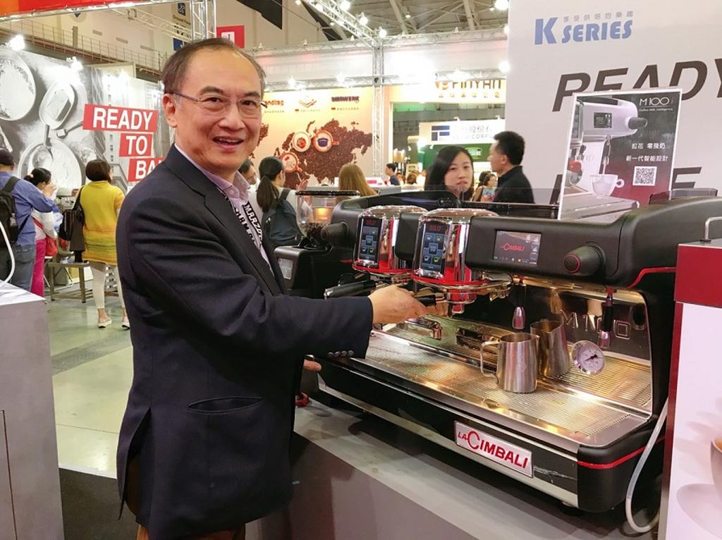 美福食品董事長張國駿親自示範於2018國際食品展中推出的第一台自動出冷奶泡的半自動機型「M100i TM」不僅能直接拉花，更媲美專業咖啡師水準。圖／賴麗如攝
