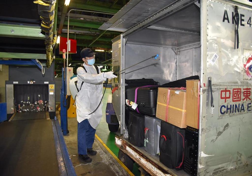入境旅客行李箱從運貨櫃搬出前，工作人員先噴灑消毒。圖／桃園機場公司提供