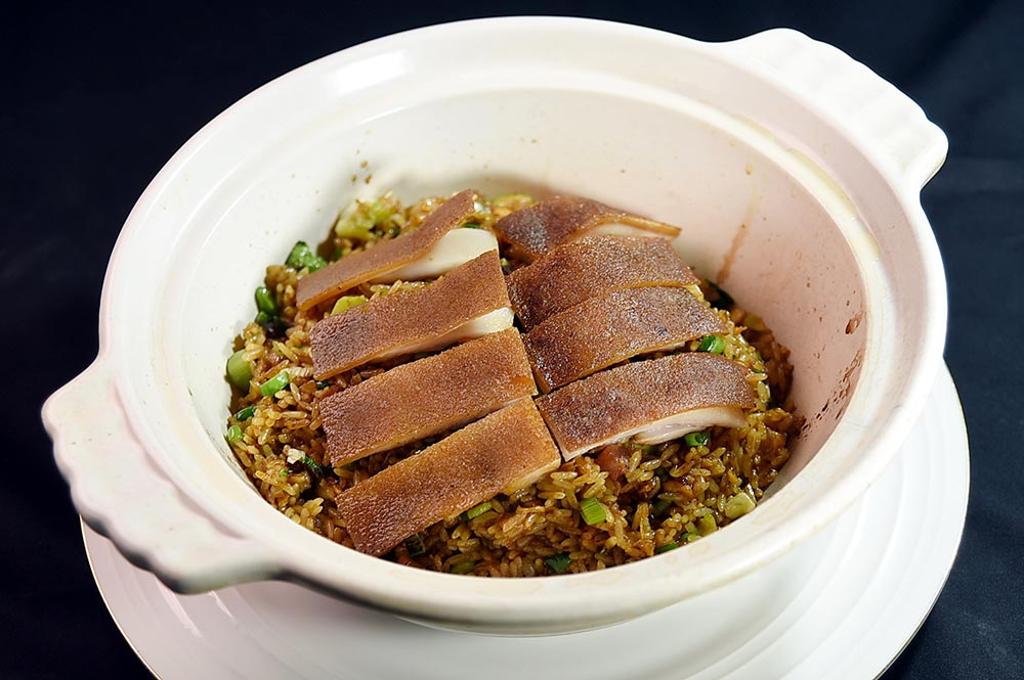 〈脆皮乳豬煲仔飯〉是以帶皮帶肉的烤乳豬，搭配港式臘味煲仔飯上桌。圖／姚舜