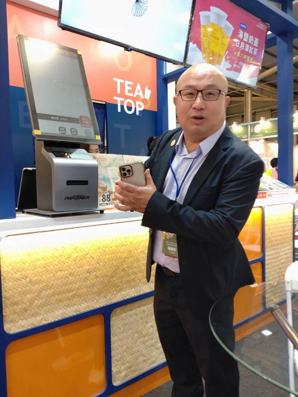 「TEA TOP第一味」執行長楊國珍21日在台中連鎖加盟展中，展出最新推出的無人點餐系統。圖／曾麗芳