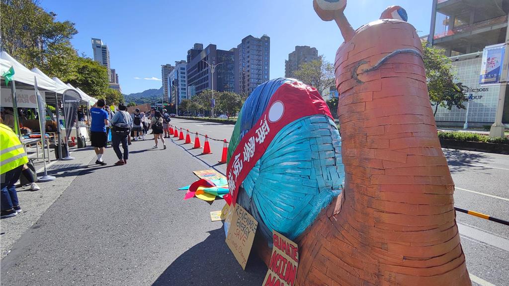 一頭蝸牛身上披著「淨零候選人」坐落在台北101前面，象徵面對2050淨零碳排的路上，各政黨參選人氣候政策及能源政策仍落後世界。（林良齊攝）