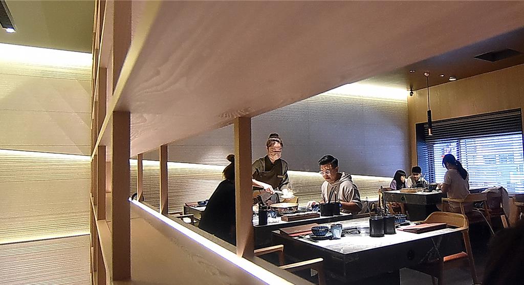 〈旬嚐〉精緻鍋物的店裝融入現代日式美學，以溫潤木格柵打造雅致空間。圖／姚舜