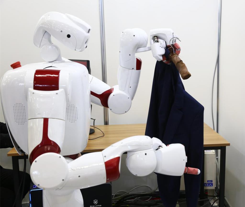 在今年日本東京舉辦的日本國際機器人展上，早稻田大學的機器人展示往衣架上掛衣服。（摘自新華社）