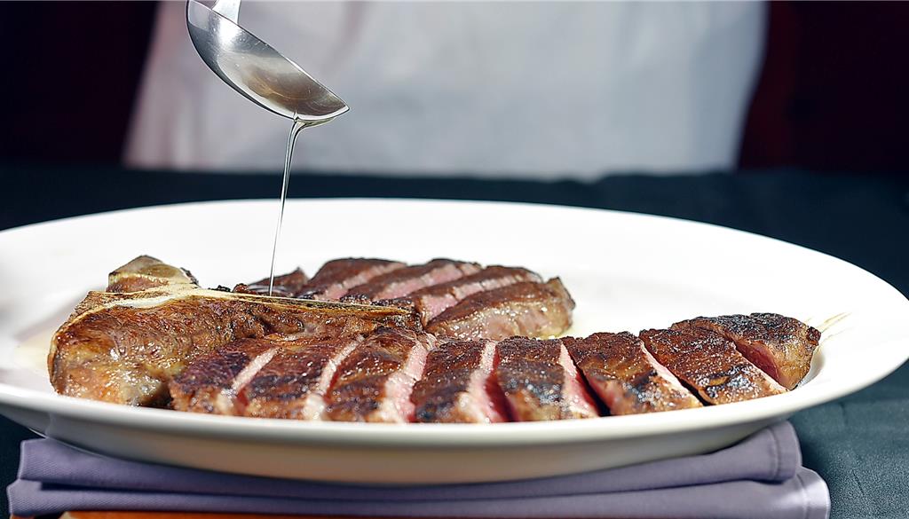 30盎司的〈美國頂級丁骨牛排〉，炙烤時會反覆將牛油淋在牛肉上，上桌時再淋上一層油脂，增添牛排香氣以及保持最佳溫度。圖／姚舜	